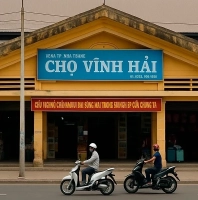 Фасад рынка Cho Vinh Hai в Нячанге, Вьетнам — желтое здание с синим знаком и проезжающими мопедами