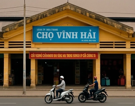 Фасад рынка Cho Vinh Hai в Нячанге, Вьетнам — желтое здание с синим знаком и проезжающими мопедами
