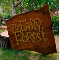 Деревянная табличка с надписью The Fairy Forest среди деревьев и зелени