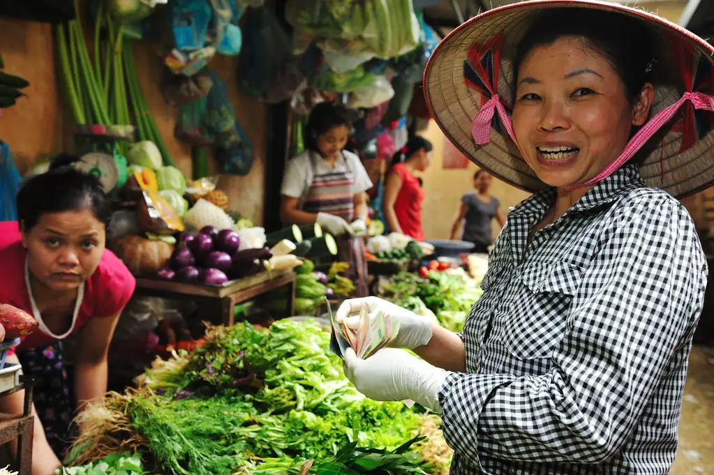 Продавщица зелени на рынке Винь Хай, улыбающаяся посетителям